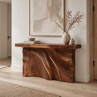 Console table with a thick slab top over a carved body of flowing ridges in a Scandinavian entryway with white walls
