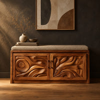 Shoe bench with two carved relief doors and a padded seat on top in a dark studio against a charcoal plaster wall