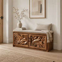 Shoe bench with two carved relief doors and a padded seat on top in a Scandinavian entryway with white walls