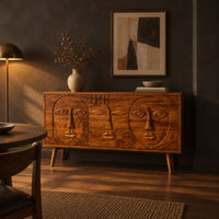 Mid century sideboard with three carved faces and four tapered legs in a dark dining room at golden hour