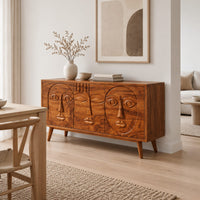 Mid century sideboard with three carved faces and four tapered legs in a Scandinavian dining room with white walls