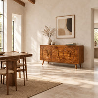 Mid century sideboard with three carved faces and four tapered legs in a bright open plan dining room