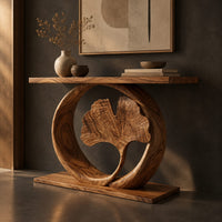 Corner detail of console table with a carved fan leaf inside a circular frame beside wood, brass and linen samples