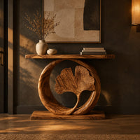 Console table with a carved fan leaf inside a circular frame in a dark entryway at golden hour