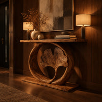 Console table with a carved fan leaf inside a circular frame in an evening entryway with walnut wall paneling