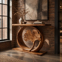 Console table with a carved fan leaf inside a circular frame in an industrial loft entryway with exposed brick