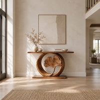 Console table with a carved fan leaf inside a circular frame in a bright open plan entryway