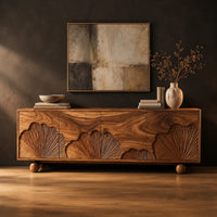 Sideboard with carved fan motifs across four panels and ball feet in a dark studio against a charcoal plaster wall