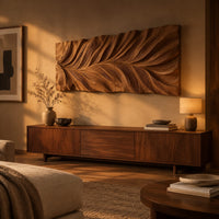 Wide wall art panel carved in a feather shaped leaf with sweeping ridges above a low console in an evening living room