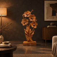 Carved wood flower sculpture with open blossoms and leaves on a block base in a dark living room at golden hour