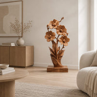 Carved wood flower sculpture with open blossoms and leaves on a block base in a Scandinavian living room with white walls