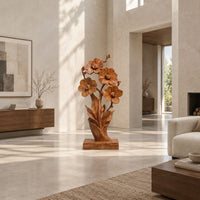 Carved wood flower sculpture with open blossoms and leaves on a block base in a bright open plan living room