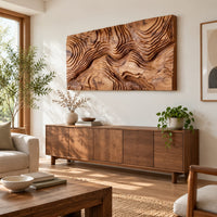 Wide wood relief wall art carved with flowing contour ridges in a bright sunroom with green plants
