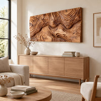 Wide wood relief wall art carved with flowing contour ridges above a light oak sideboard in daylight