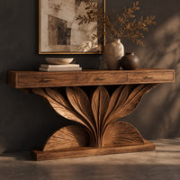 Corner detail of console table with a carved leaf fan base and three drawer fronts beside wood, brass and linen samples