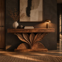 Console table with a carved leaf fan base and three drawer fronts in a dark entryway at golden hour