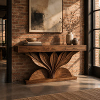 Console table with a carved leaf fan base and three drawer fronts in an industrial loft entryway with exposed brick