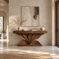 Console table with a carved leaf fan base and three drawer fronts in a bright open plan entryway