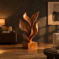 Sculpture of smooth carved leaves rising from a square block base in a dark living room at golden hour