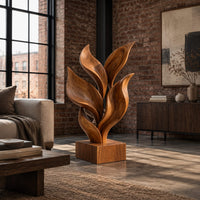 Sculpture of smooth carved leaves rising from a square block base in an industrial loft living room with exposed brick