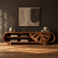 Capsule shaped tv stand with open shelves and a carved leaf panel in a dark studio against a charcoal plaster wall