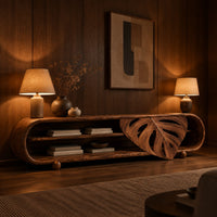 Capsule shaped tv stand with open shelves and a carved leaf panel in an evening living room with walnut wall paneling