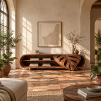 Capsule shaped tv stand with open shelves and a carved leaf panel in a bright living room with arched windows and plants