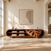 Capsule shaped tv stand with open shelves and a carved leaf panel in a bright open plan living room