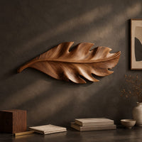 Detail of leaf shaped wall art in wood with notched lobes and carved veins beside wood, brass and linen samples