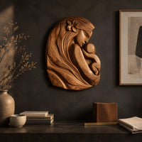 Detail of wall art carved as a mother holding her child, with long flowing hair beside wood, brass and linen samples