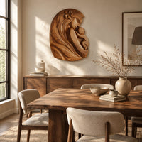 Wall art carved as a mother holding her child, with long flowing hair beside a dining table in natural light