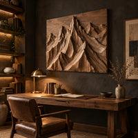 Wood wall art with carved mountain peaks in deep relief above a desk in a dark study corner