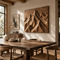 Wood wall art with carved mountain peaks in deep relief beside a dining table in natural light