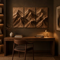 Carved mountain range wall art across three panels above a desk in a dark study corner