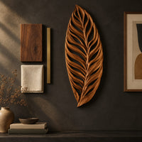 Detail of carved openwork leaf wall art with flowing veins beside wood, brass and linen samples