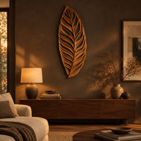 Carved openwork leaf wall art with flowing veins above a low console in an evening living room
