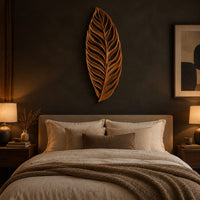 Carved openwork leaf wall art with flowing veins above a bed in a dusk lit bedroom