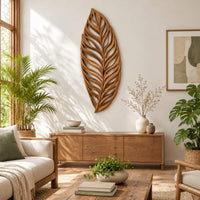 Carved openwork leaf wall art with flowing veins in a bright sunroom with green plants