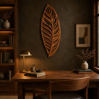 Carved openwork leaf wall art with flowing veins above a desk in a dark study corner