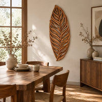 Carved openwork leaf wall art with flowing veins beside a dining table in natural light
