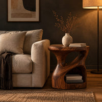 Carved pedestal side table with a twisting opening and a low open nook in a dark living room at golden hour