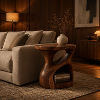 Carved pedestal side table with a twisting opening and a low open nook in an evening living room with walnut wall paneling