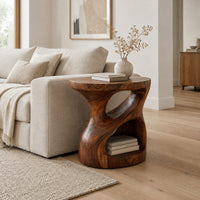 Carved pedestal side table with a twisting opening and a low open nook in a Scandinavian living room with white walls