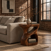 Carved pedestal side table with a twisting opening and a low open nook in an industrial loft living room with exposed brick