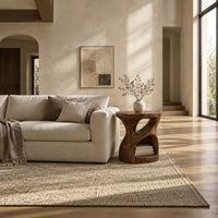 Carved pedestal side table with a twisting opening and a low open nook in a bright open plan living room
