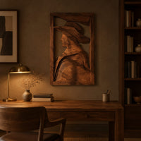 Carved wall art of a profile in a wide brim hat above a desk in a dark study corner