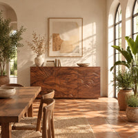 Sideboard with a carved sunrise and rolling waves across three doors in a bright dining room with arched windows and plants