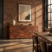 Sideboard with a carved sunrise and rolling waves across three doors in an industrial loft dining room with exposed brick