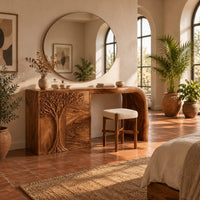 Carved tree makeup vanity with three drawers and an open knee space in a bright bedroom with arched windows and plants