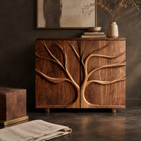 Corner detail of two door sideboard with a carved tree branch relief beside wood, brass and linen samples